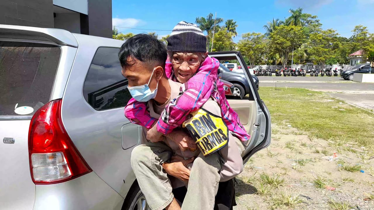 Terlihat seorang anggota Kepolisian menggendong lansia untuk mendatangi pusat vaksinasi. Foto, Tribratanews